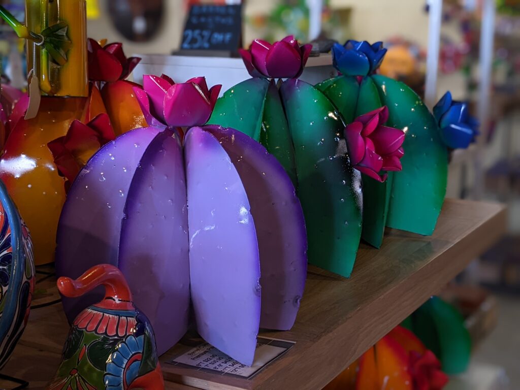 A row of metal barrel cacti painted purple, green, pink, and blue